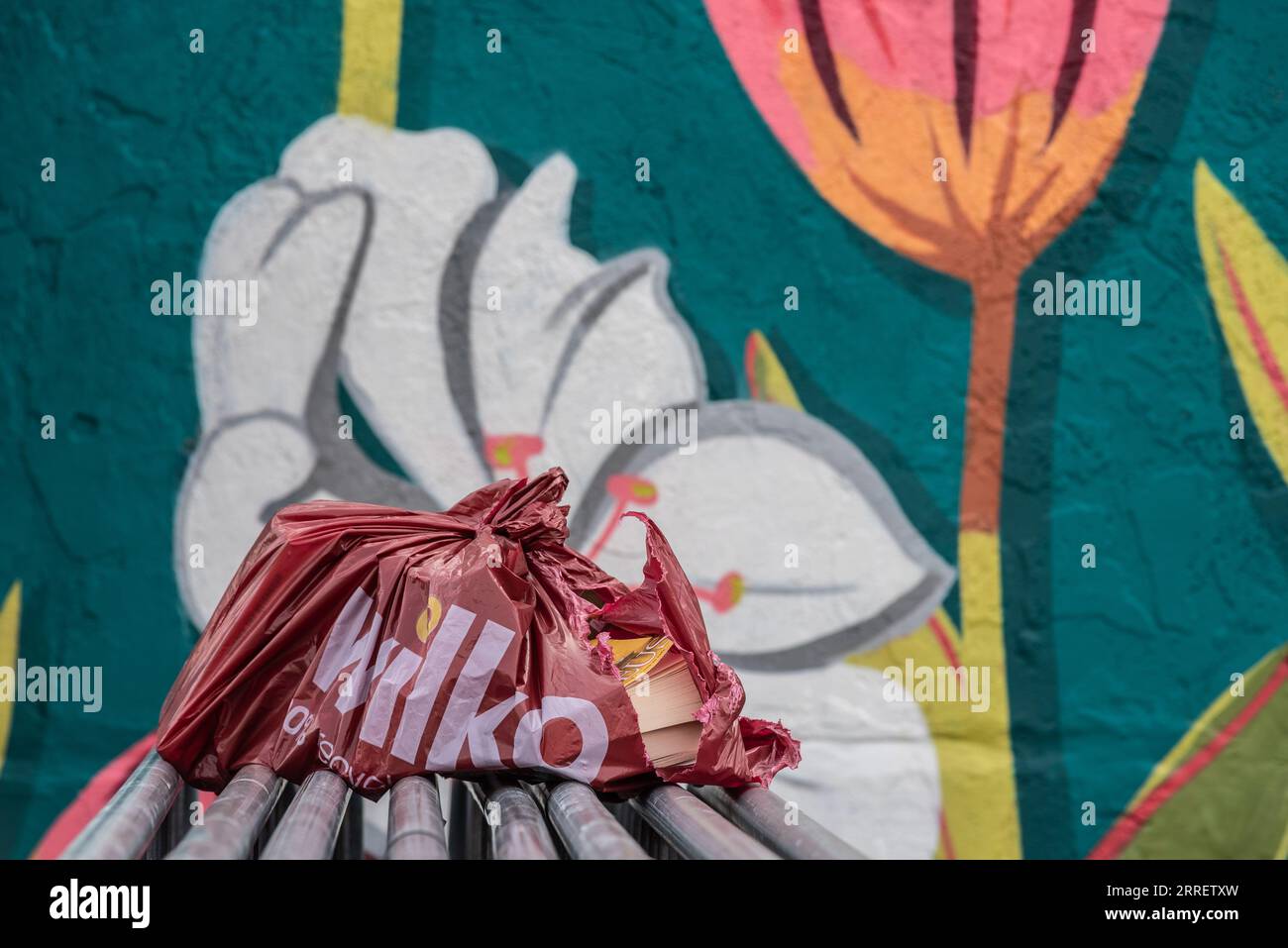 Wilko plastic carrier bag, ripped and decaying in an area with graffiti