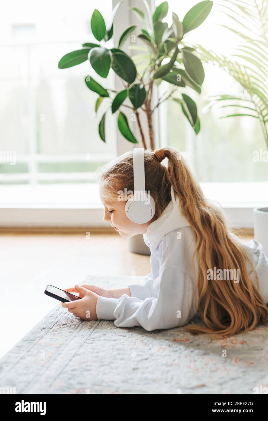 Smiling little girl listening music lying on the floor Stock Photo - Alamy