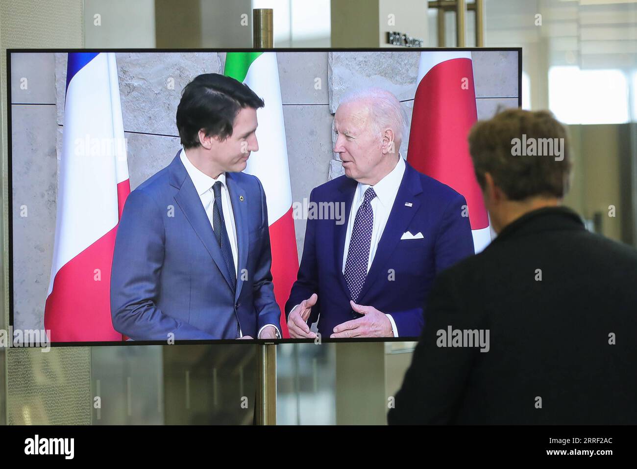 220324 -- BRUSSELS, March 24, 2022 -- A man watches a screen displaying U.S. President Joe Biden R and Canadian Prime Minister Justin Trudeau attending a group photo session during a meeting of G7 Leaders at the NATO headquarters in Brussels, Belgium, March 24, 2022.  BELGIUM-BRUSSELS-G7-MEETING ZhengxHuansong PUBLICATIONxNOTxINxCHN Stock Photo