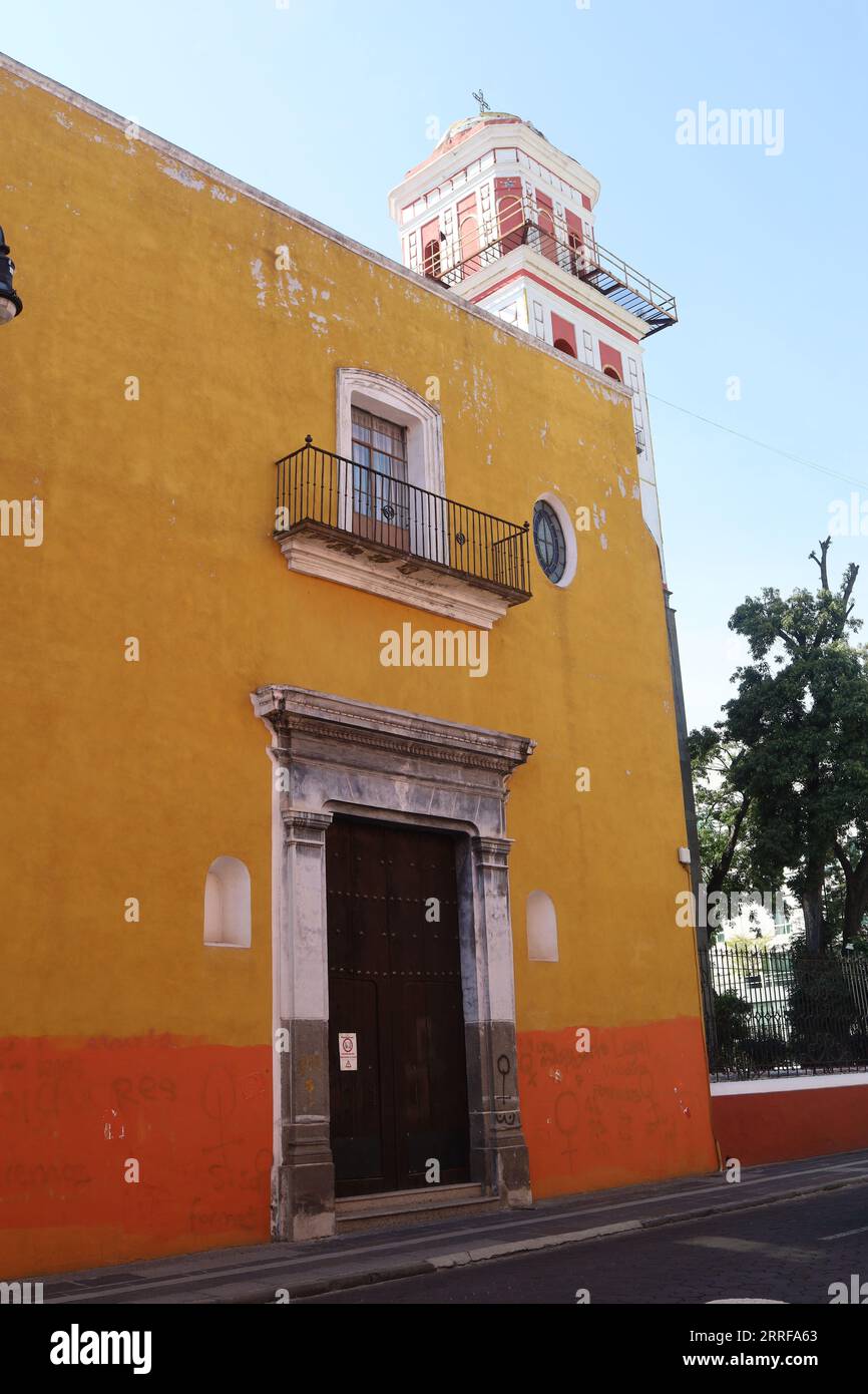 yellow and orange house with church tower in the bag in Puebla, México Stock Photo