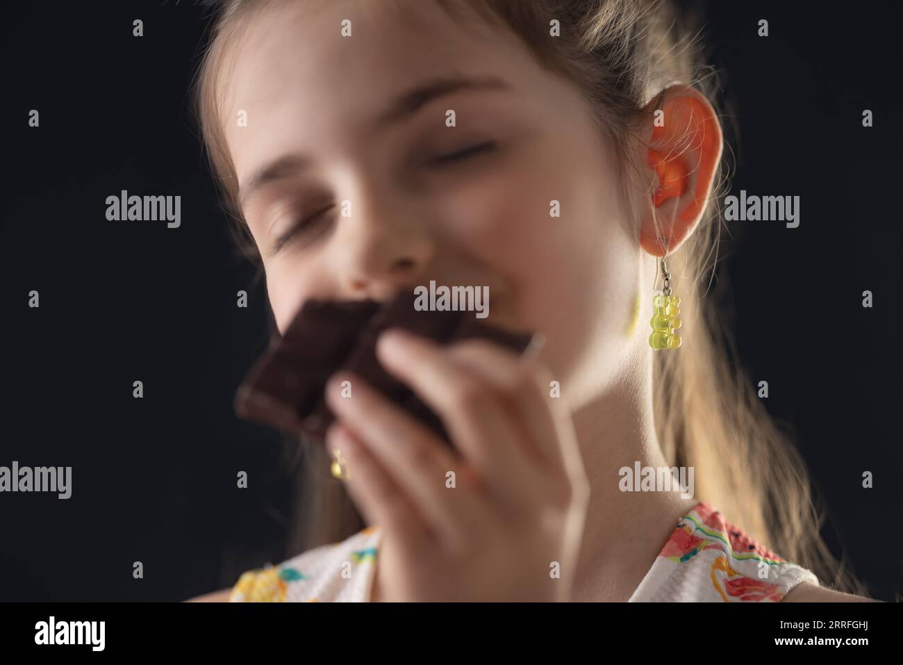 Chocolate and pretty hungry little woman portrait. Beautiful girl ready to eat chocolate bar. Stock Photo