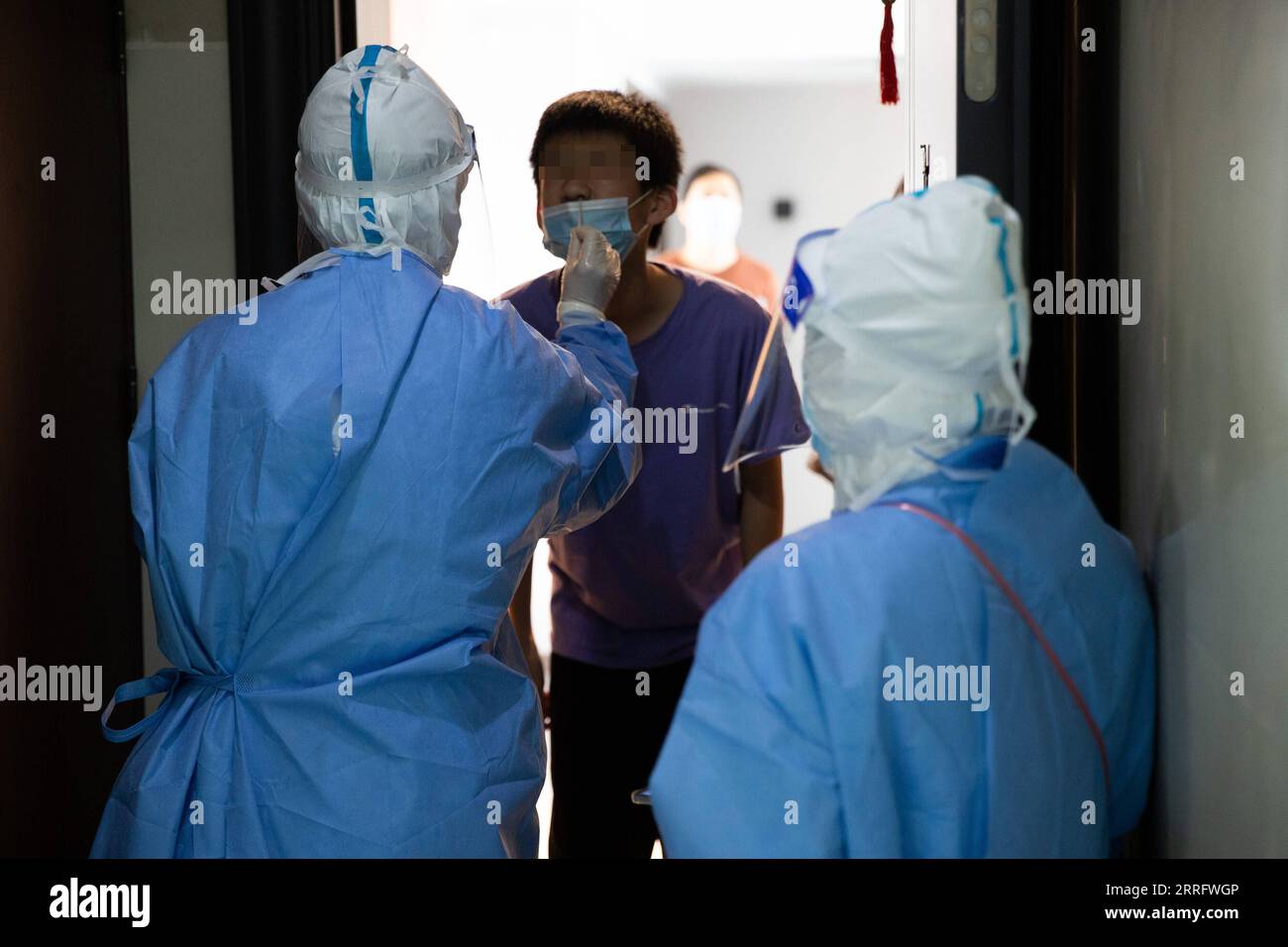 220427 -- SHANGHAI, April 27, 2022 -- Tian Ge L and He Yanping take a swab sample from a resident for nucleic acid test at a building under closed-off management in Beicai Town of east China s Shanghai, April 26, 2022. Tian Ge and He Yanping, both general practitioners, conduct a door-to-door nucleic acid test for residents without negative results in mass testing or antigen testing in Beicai.  CHINA-SHANGHAI-BEICAI-NUCLEIC ACID TEST CN JinxLiwang PUBLICATIONxNOTxINxCHN Stock Photo