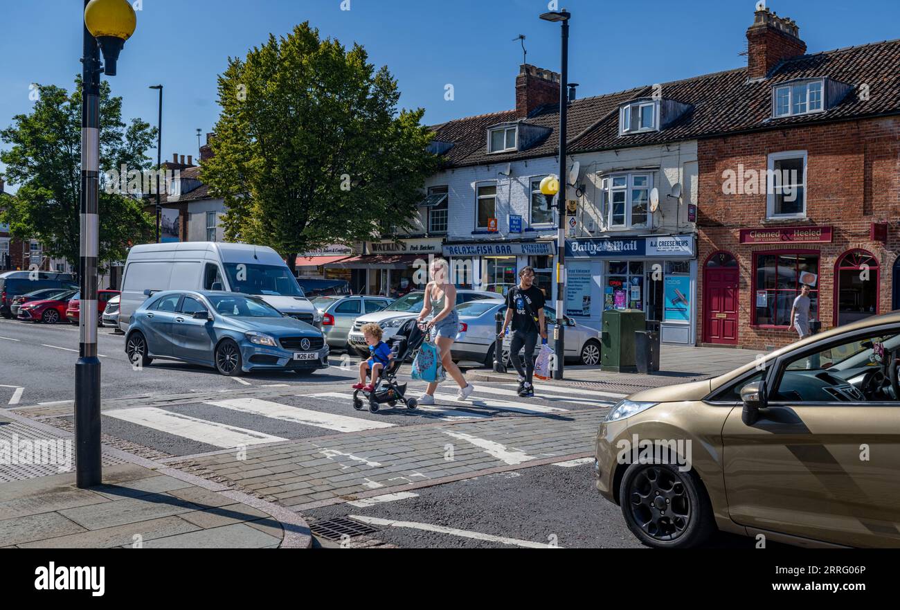 Grantham Lincolnshire - Zebra crossing or a pedestrian crossing on a very busy street with a young mother crossing with her child in a pushchair Stock Photo