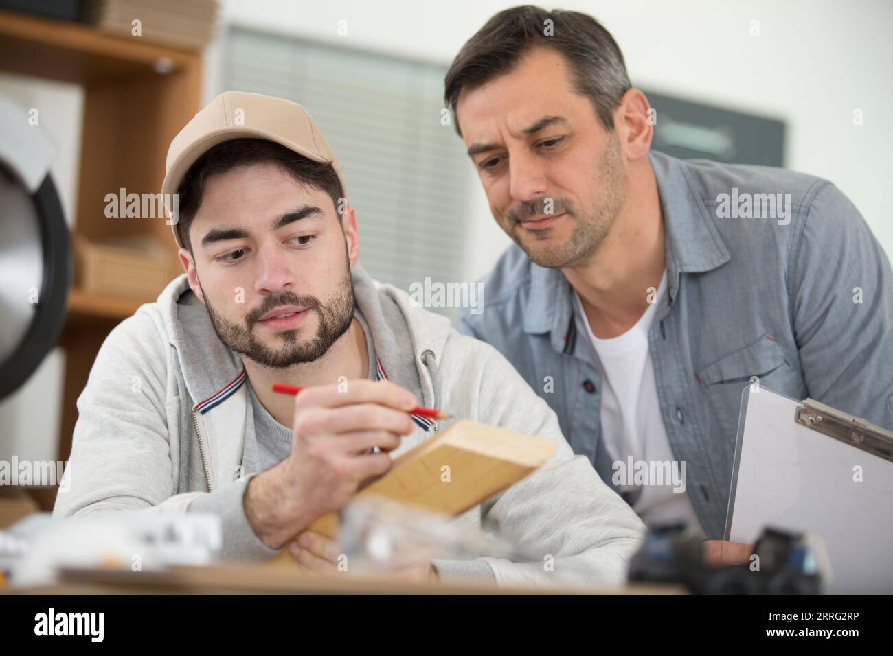 two workers or craftsman apprentices work together in the workshop Stock Photo