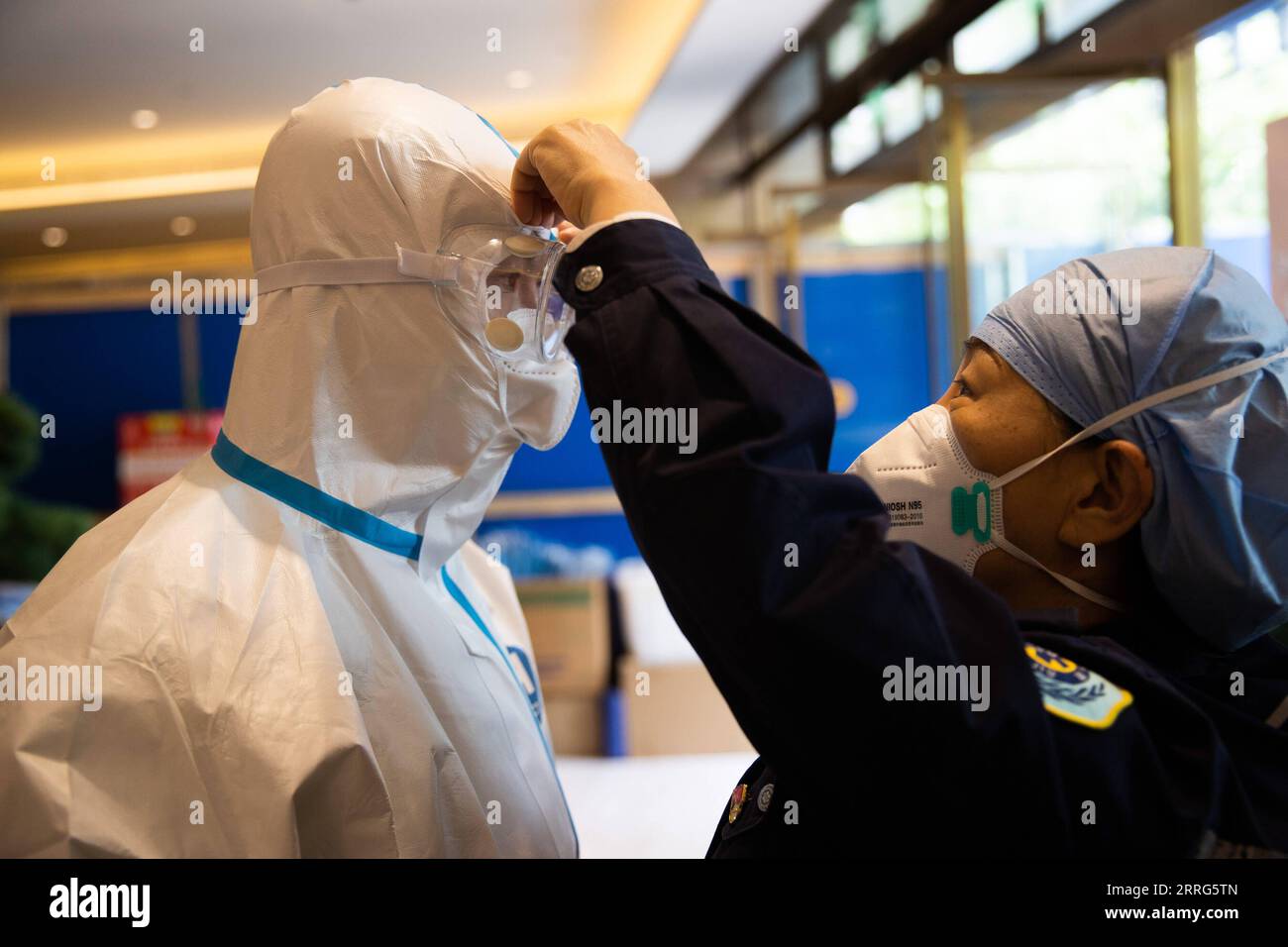 220510 -- SHANGHAI, May 10, 2022 -- Zhang Ying R helps Meng Xiangjun wear protective suit at the headquarters of a medical emergency team on Caoyang Road in east China s Shanghai, May 9, 2022. A medical emergency team consisting of 108 members with 50 ambulances from north China s Tianjin has arrived at Shanghai to assist in the city s public medical emergency service amid the COVID-19 resurgence.  CHINA-SHANGHAI-MEDICAL TEAM-COVID-19-AID CN JinxLiwang PUBLICATIONxNOTxINxCHN Stock Photo