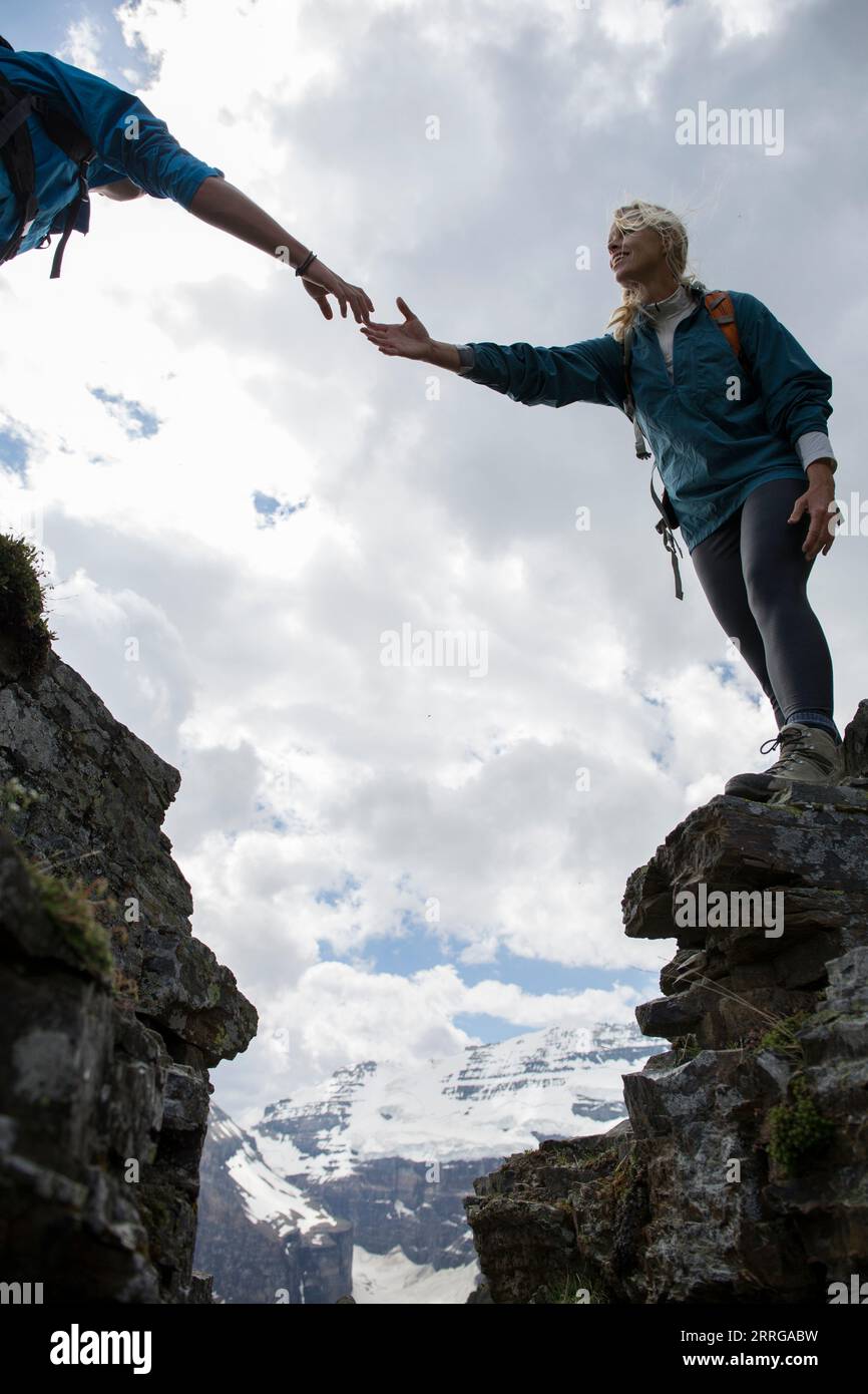 Climber offers assitance to teammate, mtns Stock Photo