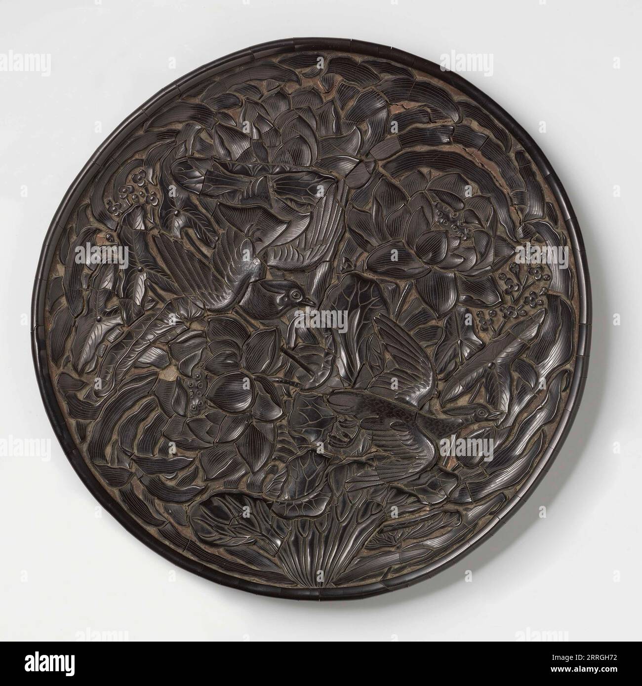 Dish, Zhang Cheng, c. 1300 - c. 1325 wood, lacquer, d 32.5cm This carved dish features a pair of birds in flight against a background of lotus flower c. 1300 - c. 1325 Yuan-dynasty (1279-1368) wood, lacquer Stock Photo