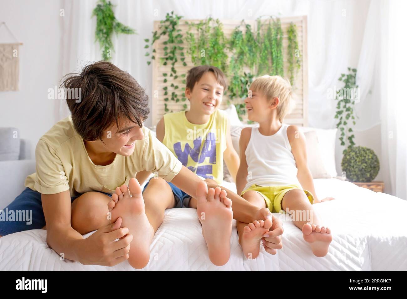 Happy positive children, tickling on the feet, having fun together, boy brothers at home having wonderful day of joy together Stock Photo