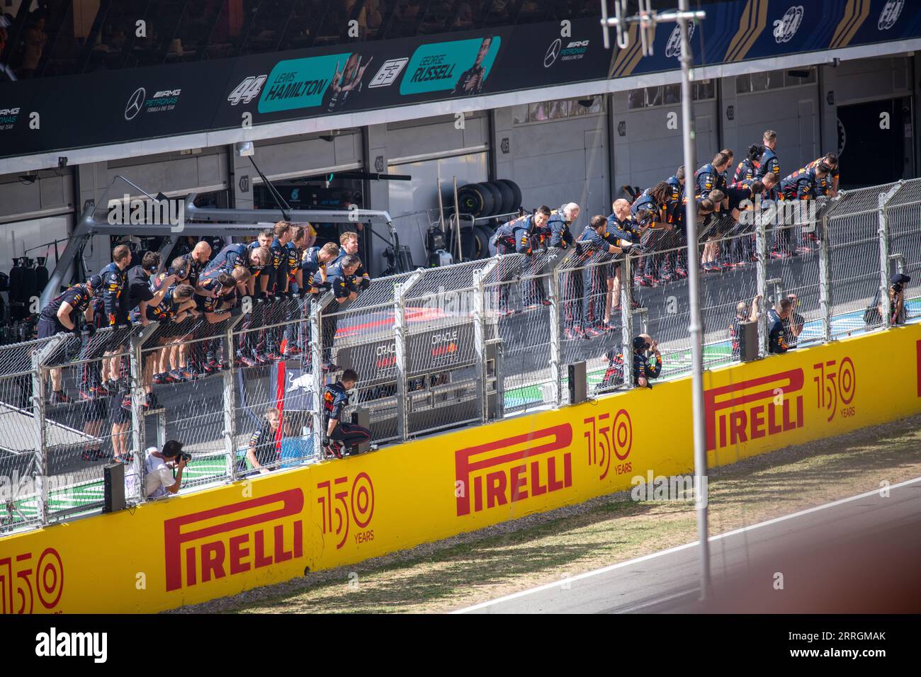 Red Bull pit crew standing on paddock fences, eagerly awaiting Max Verstappen's win at the Spanish Grand Prix. Stock Photo