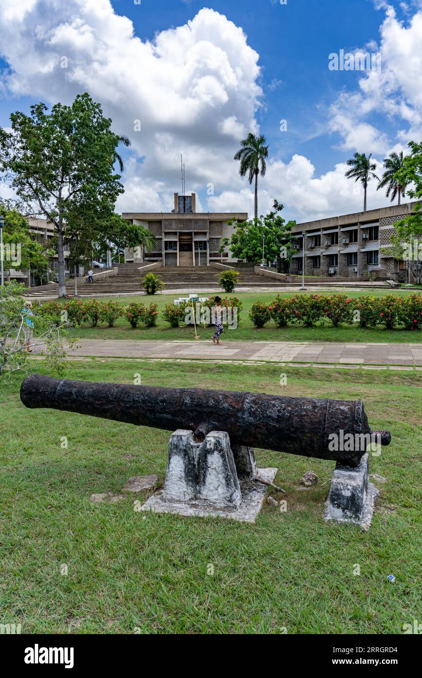 A colonial-era cannon in Independence Plaza in the capital city of Belmopan, Belize.  The National Assembly Building is behind. Stock Photo