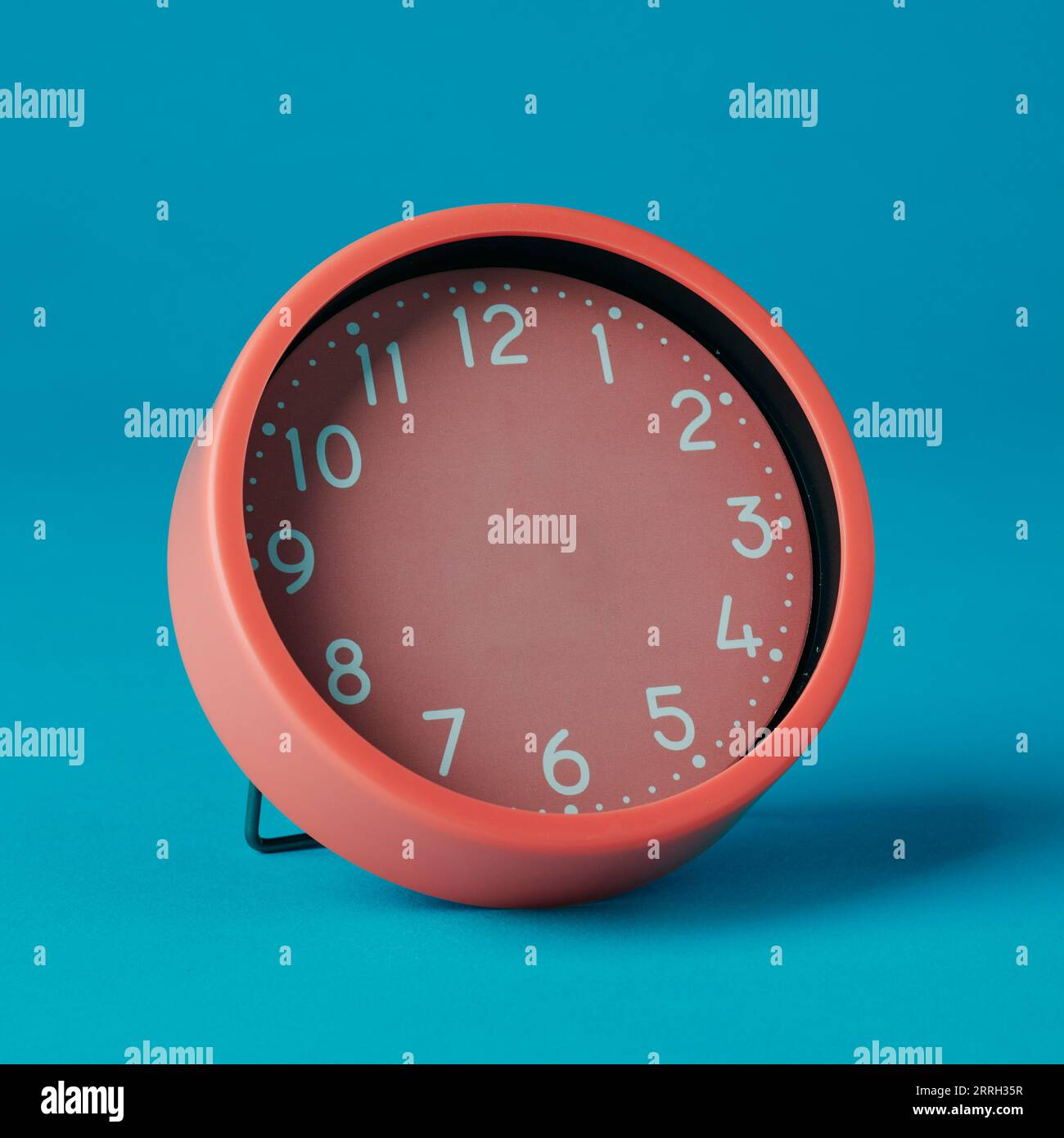 closeup of a pink clock without hands on a blue background Stock Photo