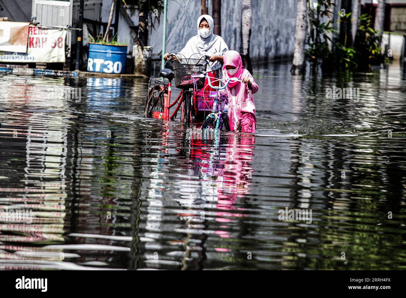 220613 -- SIDOARJO, June 13, 2022 -- A mother and her daughter push their bikes through flood water after heavy rain at Waru in Sidoarjo, East Java, Indonesia, June 13, 2022. Photo by /Xinhua INDONESIA-SIDOARJO-FLOOD Kurniawan PUBLICATIONxNOTxINxCHN Stock Photo