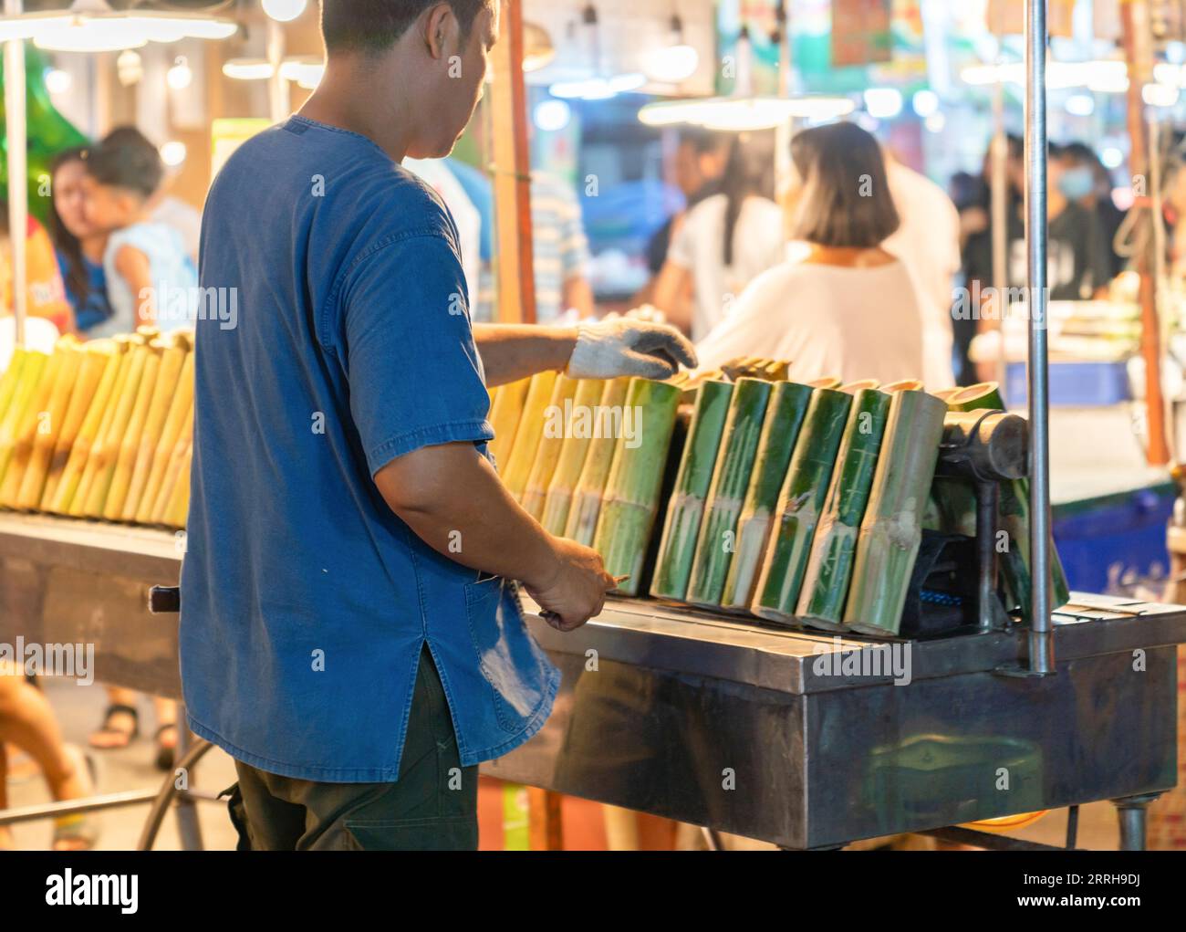 Merchant flip glutinous rice roasted in bamboo on grill in street food ...