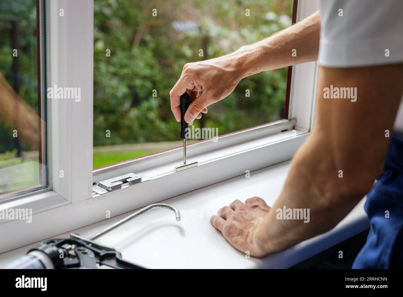 worker adjusting plastic PVC window. maintenance and repair. banner with copy space Stock Photo