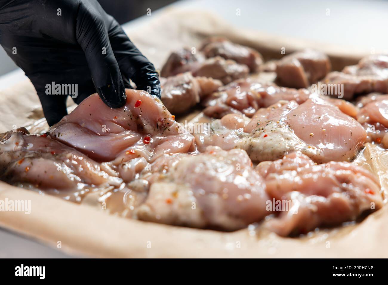 hand puts raw chicken fillet meat on pan before cooking in oven at home Stock Photo