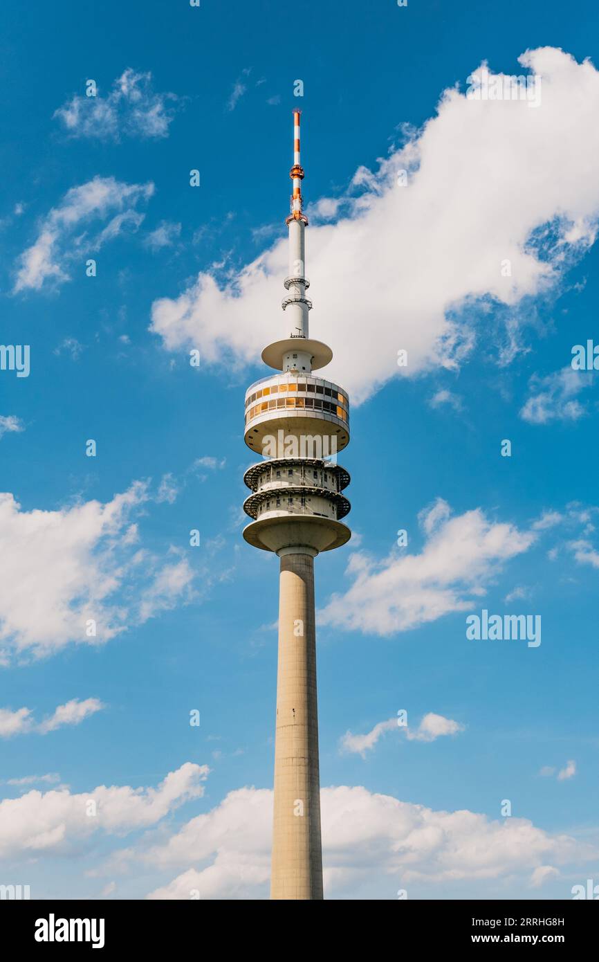 Tall and sharp Olympiaturm tower in the center with dramatic blue summer sky and white clouds in the background Stock Photo