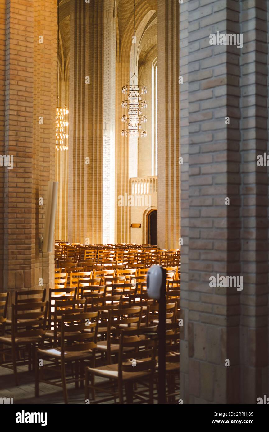 Interior of Grundtvig's Church with rows of wooden chairs and a chandelier in the background Stock Photo