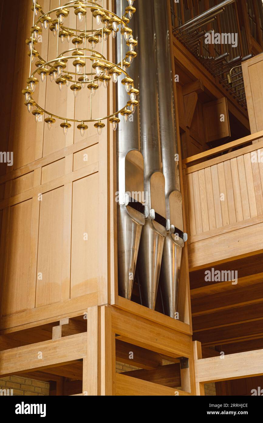 A close up of the main west organ (the metal pipes and wooden construction) in Grundtvig's Church with a chandelier hanging in front of it Stock Photo