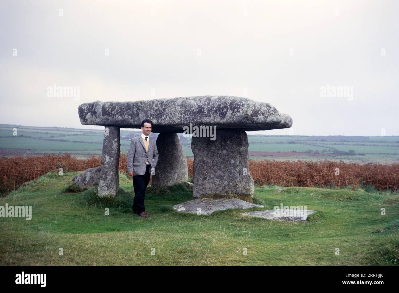 Man standing by Lanyon Quoit prehistoric dolmen, Morvah, Cornwall, England, UK 1967 Stock Photo