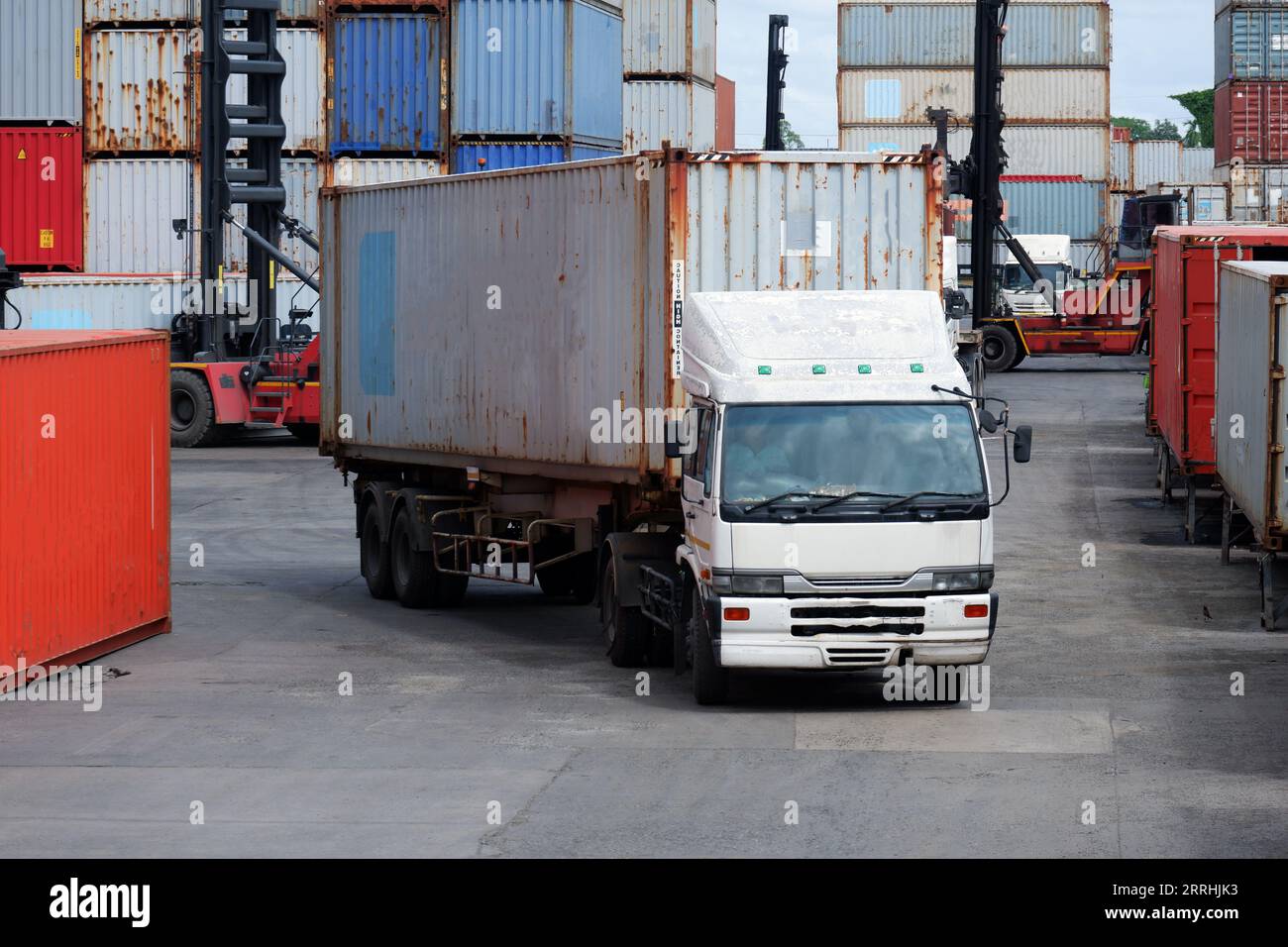 Freight trucks, container boxes in logistic shipping yard with stacks