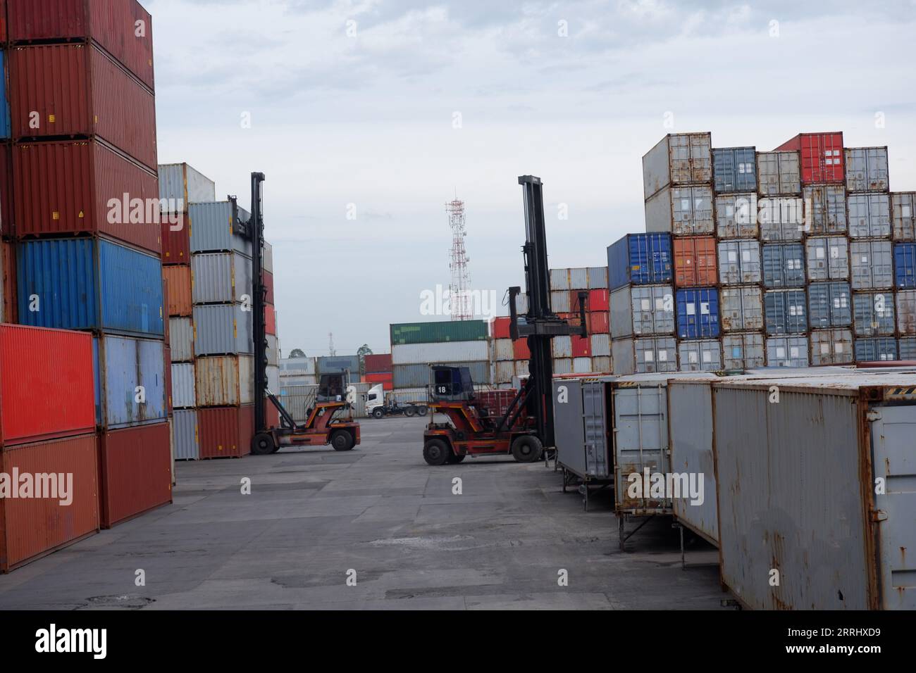 Forklift trucks handling freight, container boxes in logistic delivery yard with stacks of cargo containers. Stock Photo