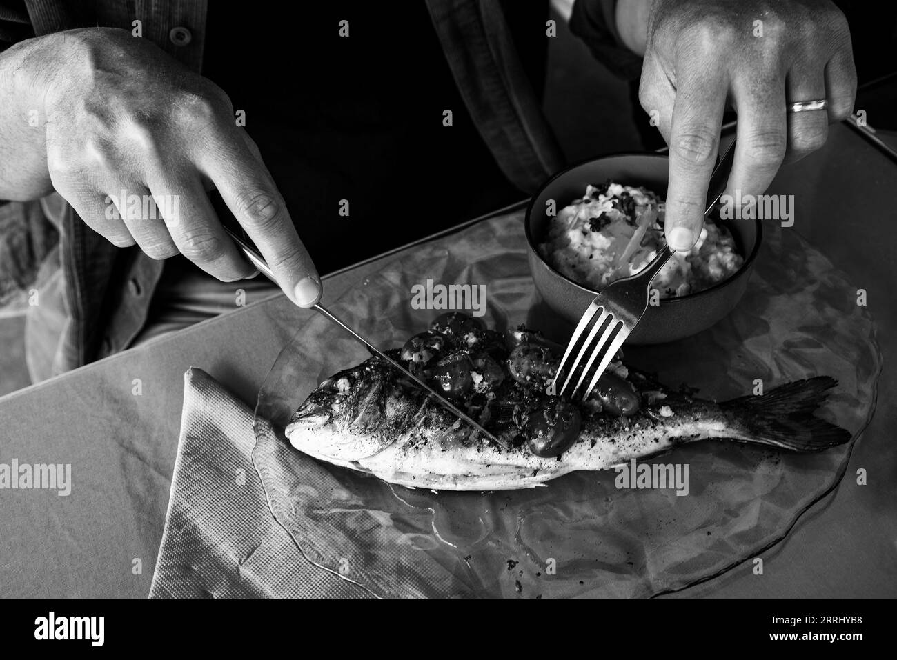 Man eating grilled dorada fish and rice with celery root puree in a seaside provencal restaurant in Camargue, France. Black white historic photo. Stock Photo