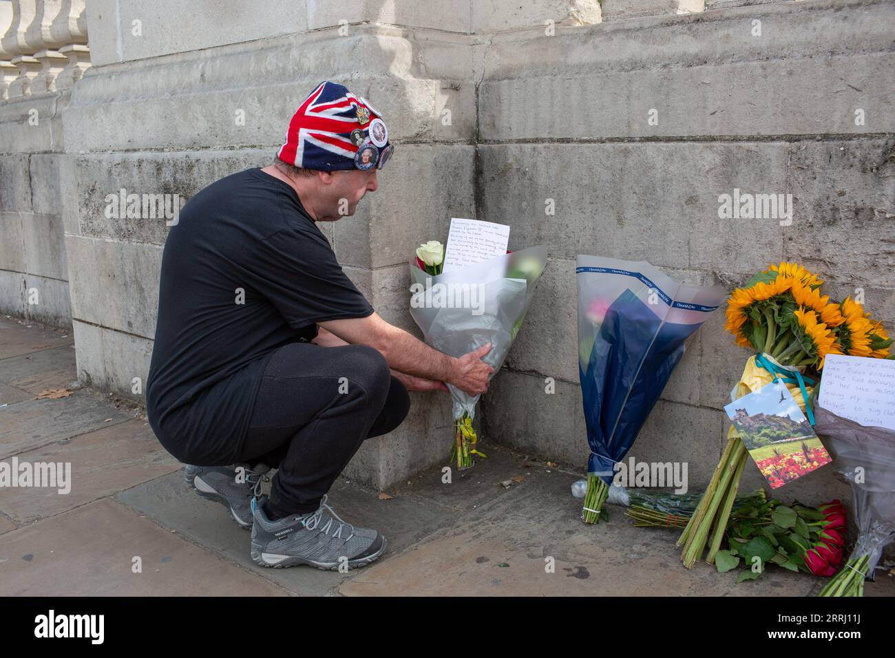 London, 8th, sep. 2023 Royalist John Loughrey lays Flowers and a card down by the wall at Buckingham Palace to mark the first anniversary of the death of Queen Elizabeth II. And sits on green next to Buckingham Palace with friends credit Richard Lincoln/Alamy Live Stock Photo