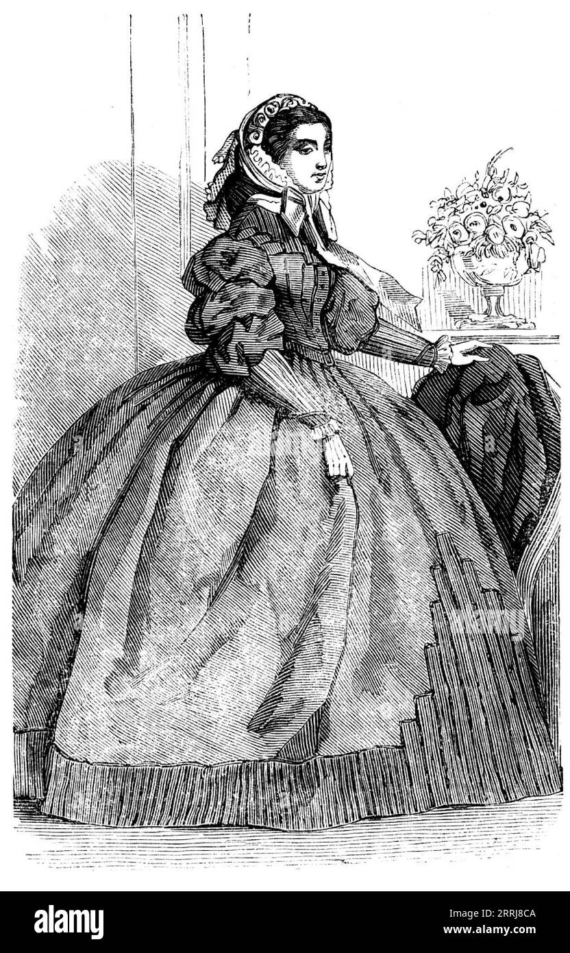 Fashions for November - Dress of Silver-Grey Silk, 1858. 'The skirt is edged with a trimming formed of the same material as the dress, disposed in very small plaits, and headed by a row of velvet. In front a plaiting of the same kind forms a sort of half tablier, rising only to the height of the knees. The corsage is high, and the upper part is composed entirely of small folds or plaits. The sleeves are in three puffs at the upper part, and from the elbow to the wrist they are in small plaits, setting closely to the arm. Bonnet of white velours &#xe9;pingl&#xe9;, with a voilette of white lace Stock Photo
