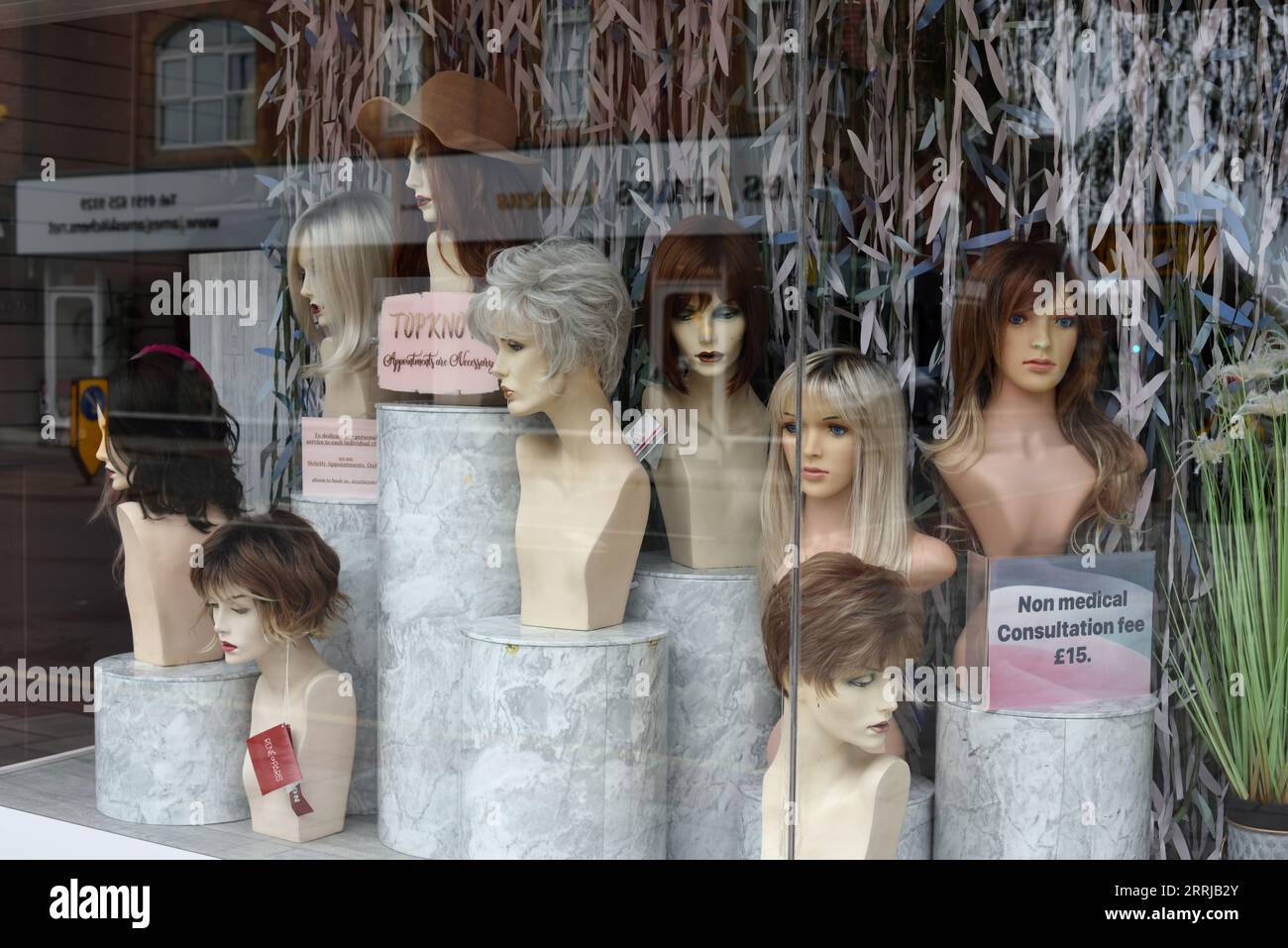 Hairdressers or Hairdresser Shop Window, Display Window or Store Window with Display of Mannequins or Dummies with Wigs and Topknots West Kirby E Stock Photo