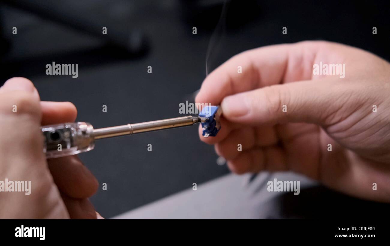 An engineer connects two parts of a radio circuit with a soldering iron