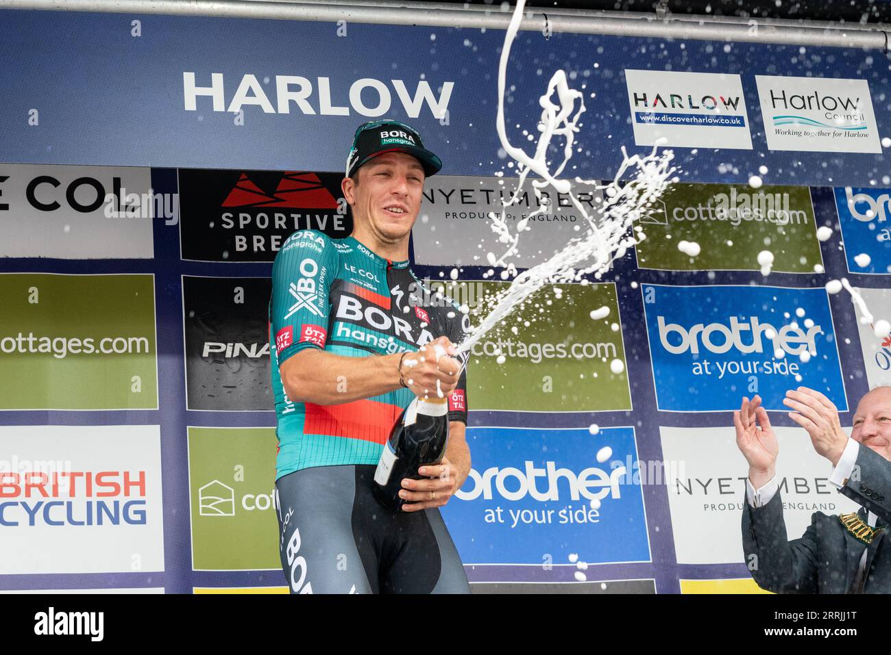 Harlow, Essex, UK. 8th Sep, 2023. The riders have raced from the start in Southend on Sea to the finish line in Harlow after 91 miles of competing through the Essex countryside. First across the line in a bunch sprint was Danny van Poppel of team Bora-Hansgrohe, celebrating his win by spraying champagne Stock Photo