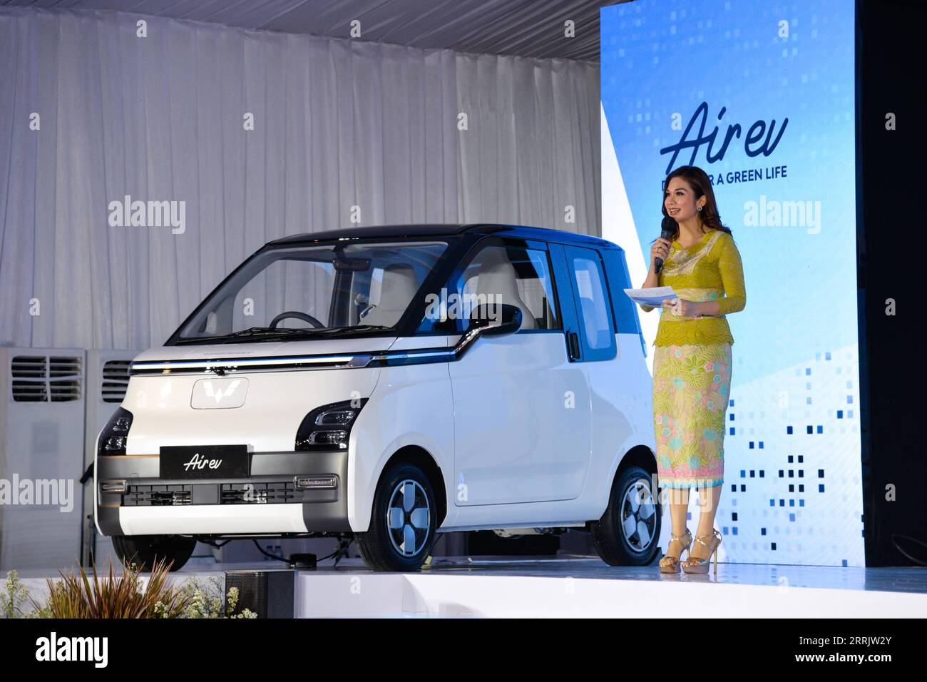 220809 -- BEKASI, Aug. 9, 2022 -- A hostess briefs people on Wuling Air EV during the roll-out ceremony at Wuling s production factory in Bekasi, West Java province, Indonesia, Aug. 8, 2022. SAIC-GM-Wuling SGMW, a major Chinese automobile manufacturer, through its local unit SGMW Motor Indonesia Wuling, on Monday launched here its production of the electric vehicle in Indonesia, named Wuling Air EV. INDONESIA-BEKASI-CHINA-WULING AIR EV-ROLL-OUT CEREMONY XuxQin PUBLICATIONxNOTxINxCHN 220809 -- BEKASI, Aug. 9, 2022 -- A hostess briefs people on Wuling Air EV during the roll-out ceremony at Wulin Stock Photo