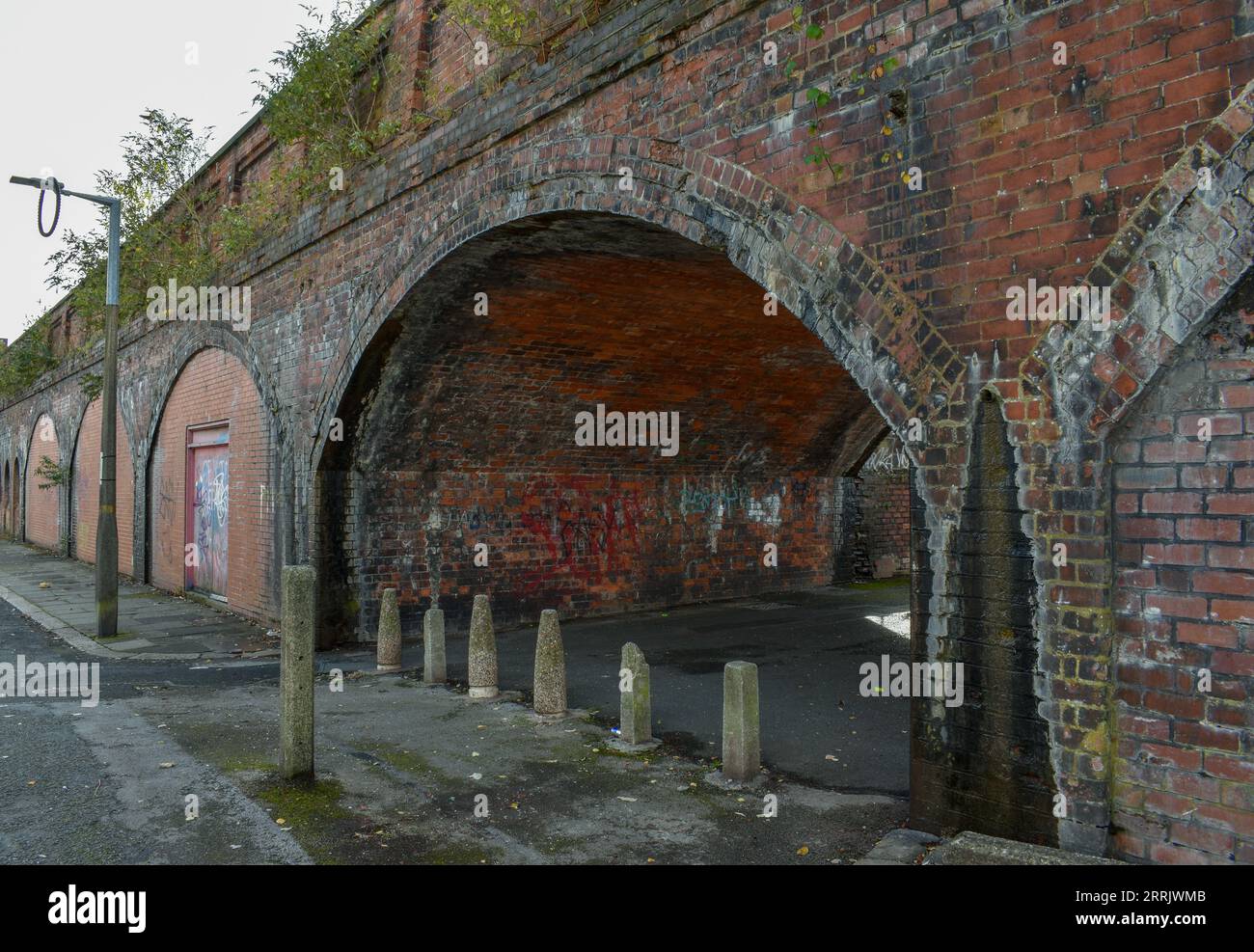 An old brick walkway covered in graffiti leading under a railway line in Barrow. Stock Photo