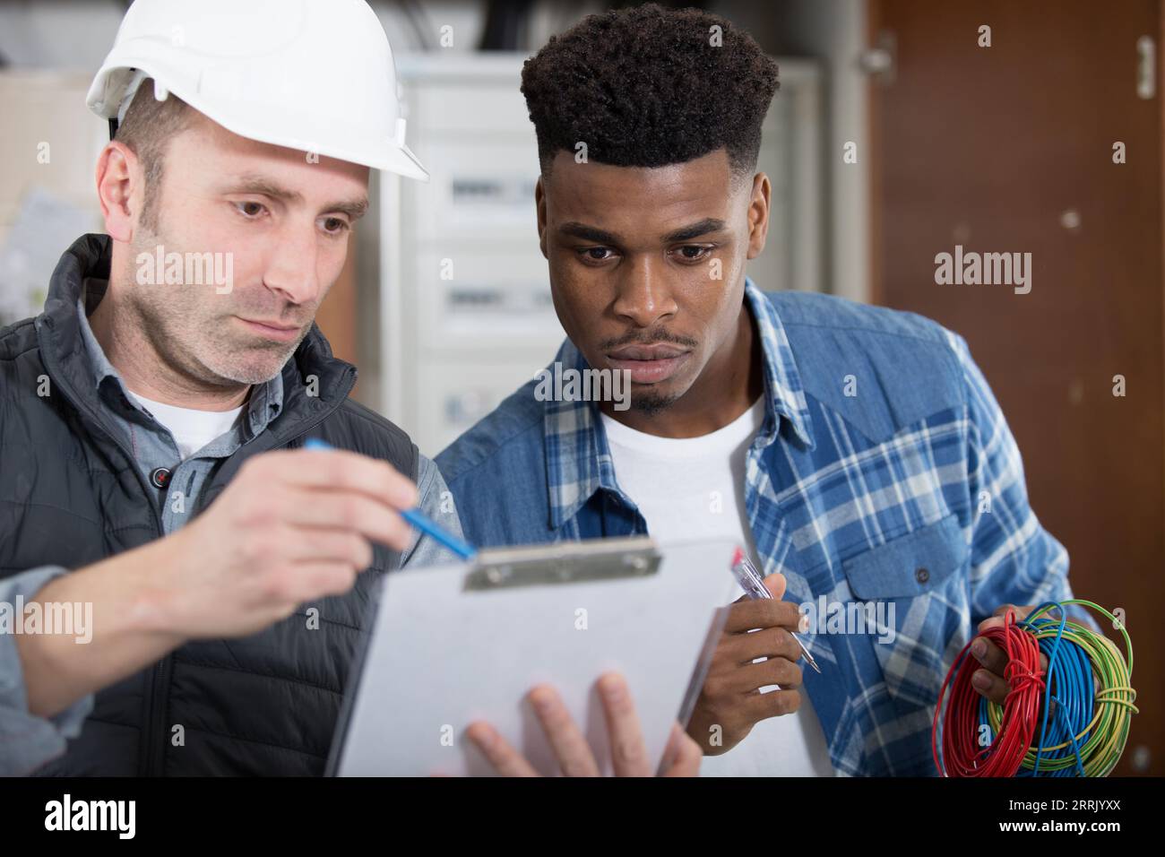 two workers in uniform smiling and holding clipboards Stock Photo