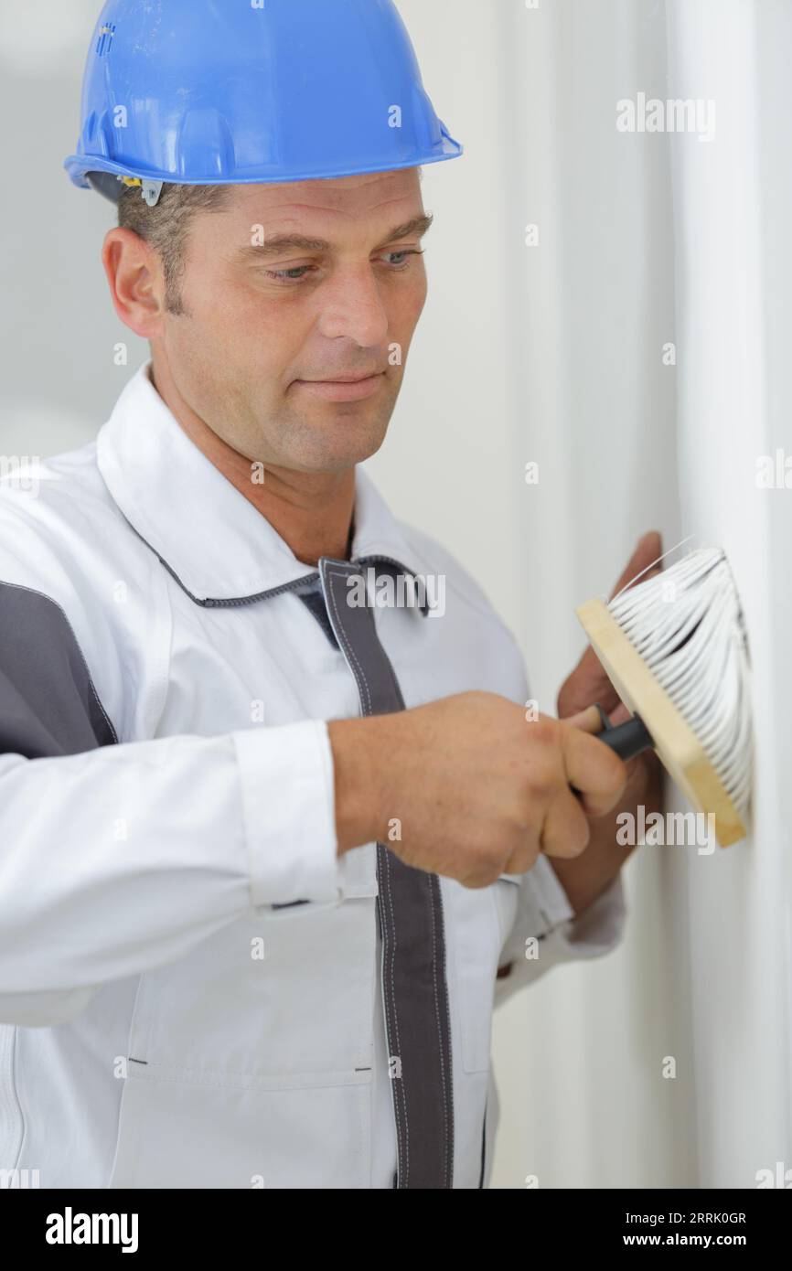 male decorator using large brush on wall Stock Photo