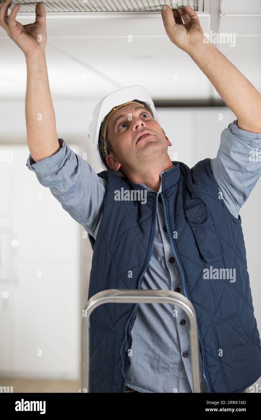 man in builder uniform installing suspended ceiling Stock Photo - Alamy
