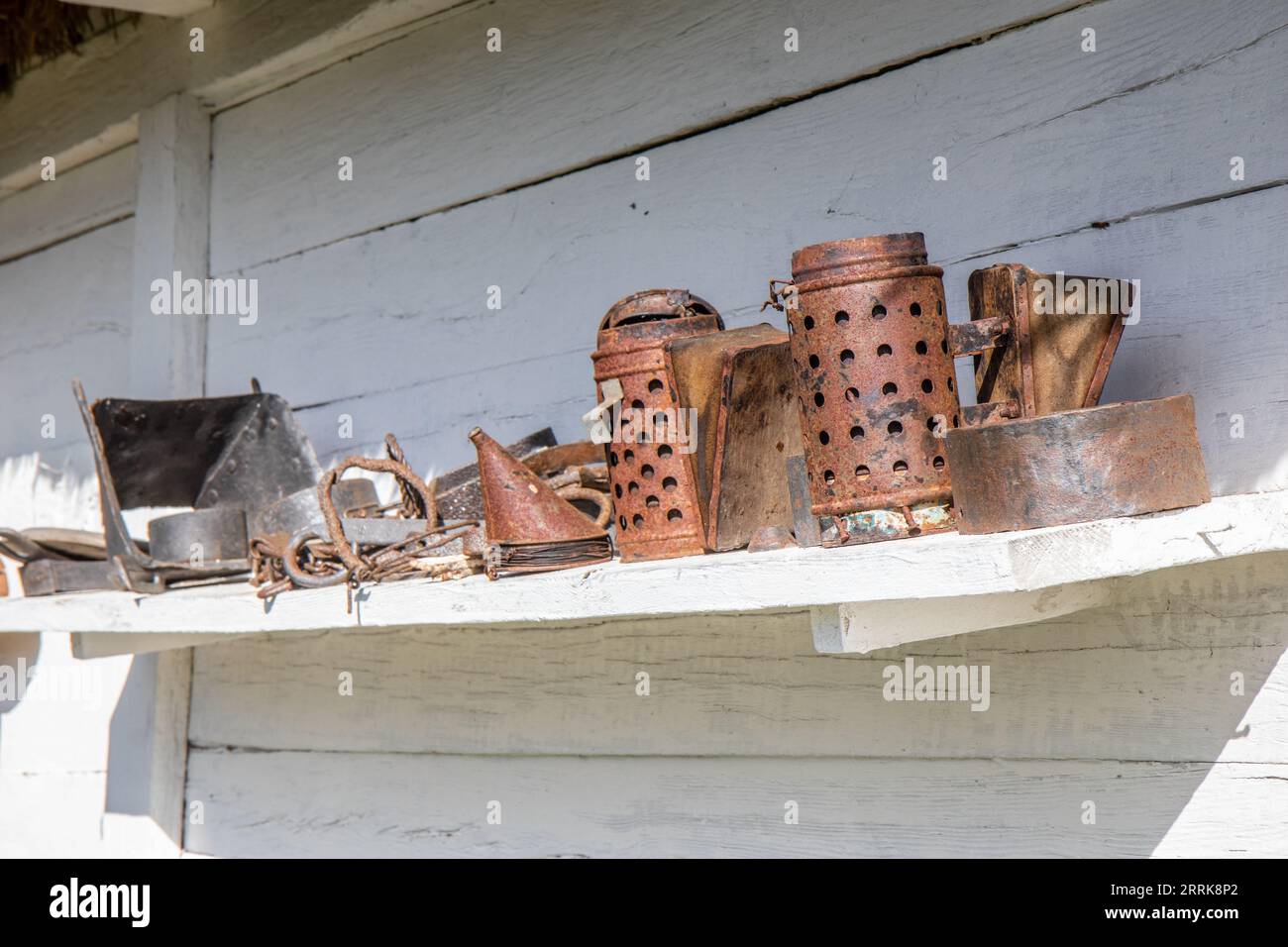 Old rusty beekeeping tools on outdoor shelf Stock Photo