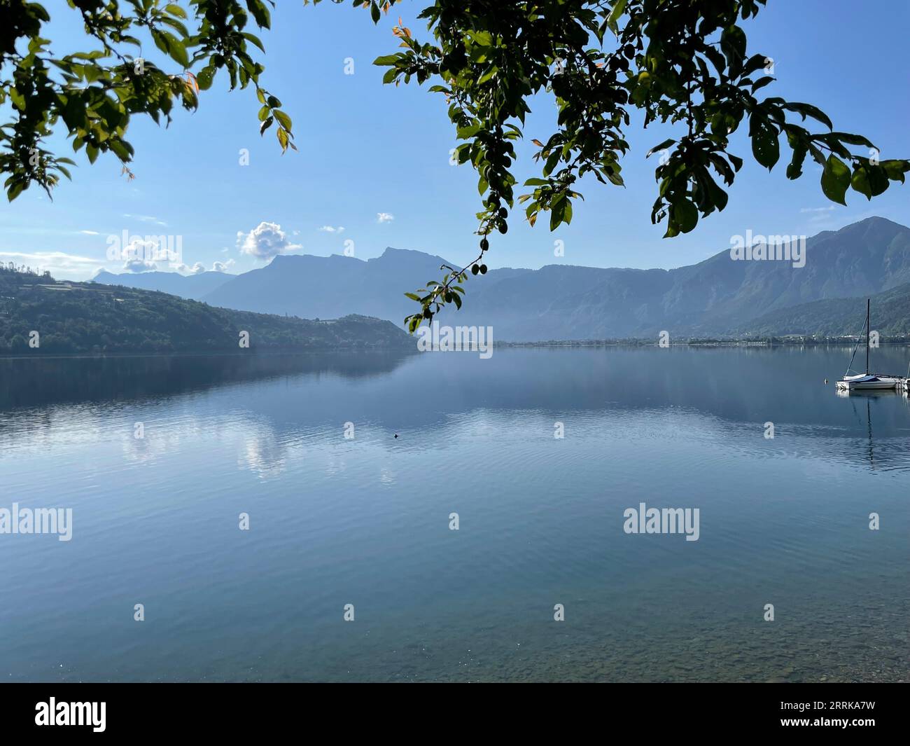 View of the calm Lake Caldonazzo in Trentino, Lago di Caldonazzo, Suganertal, Valsugana, Levico Lake, Lago di Levico, boat, nature, water, mountains, activity, sun, clouds, Caldonazzo, Trentino Alto Adige, Italy Stock Photo
