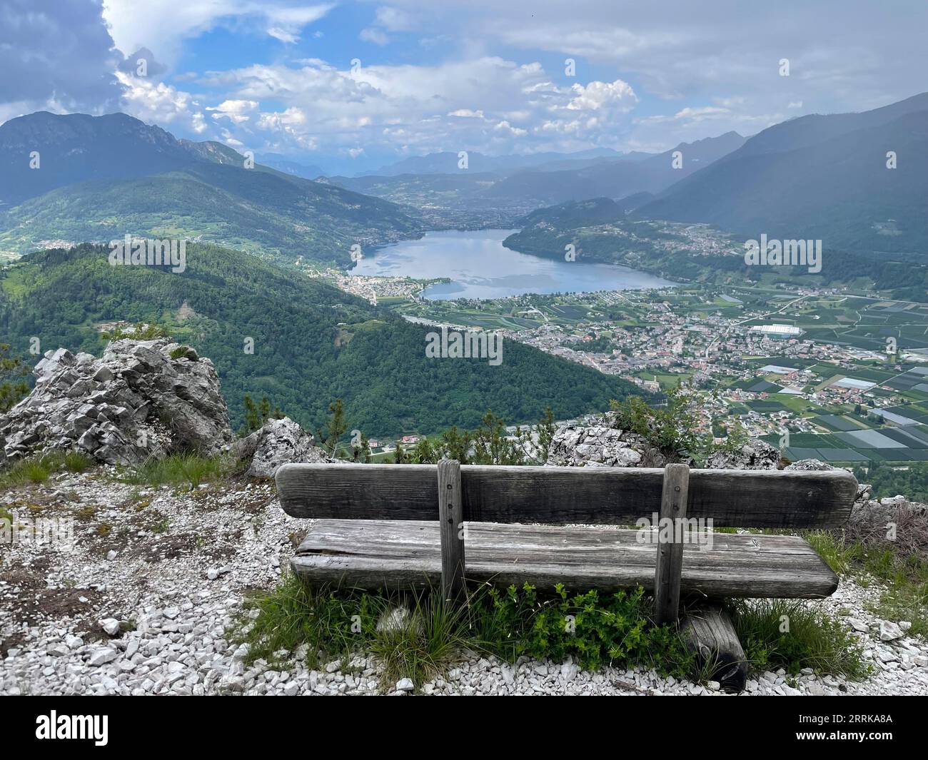 View of Lake Caldonazzo in Trentino with a bench in the foreground, Caldonazzo and Calceranica al Lago, Lago di Caldonazzo, Suganertal, Valsugana, Levico Lake, Lago di Levico, nature, water, mountains, activity, sun, clouds, Caldonazzo, Trentino Alto Adige, Italy Stock Photo