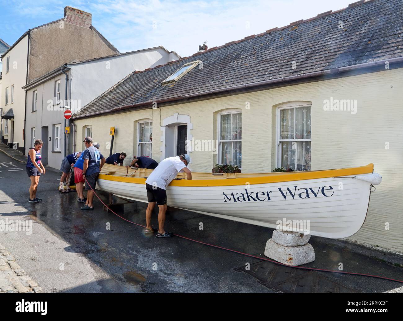 Cawsand Square in south east Cornwall on the often overlooked Rame Peninsula. The Rame Gig Club team givng maintenance to the Maker Wave gig boat on a Stock Photo