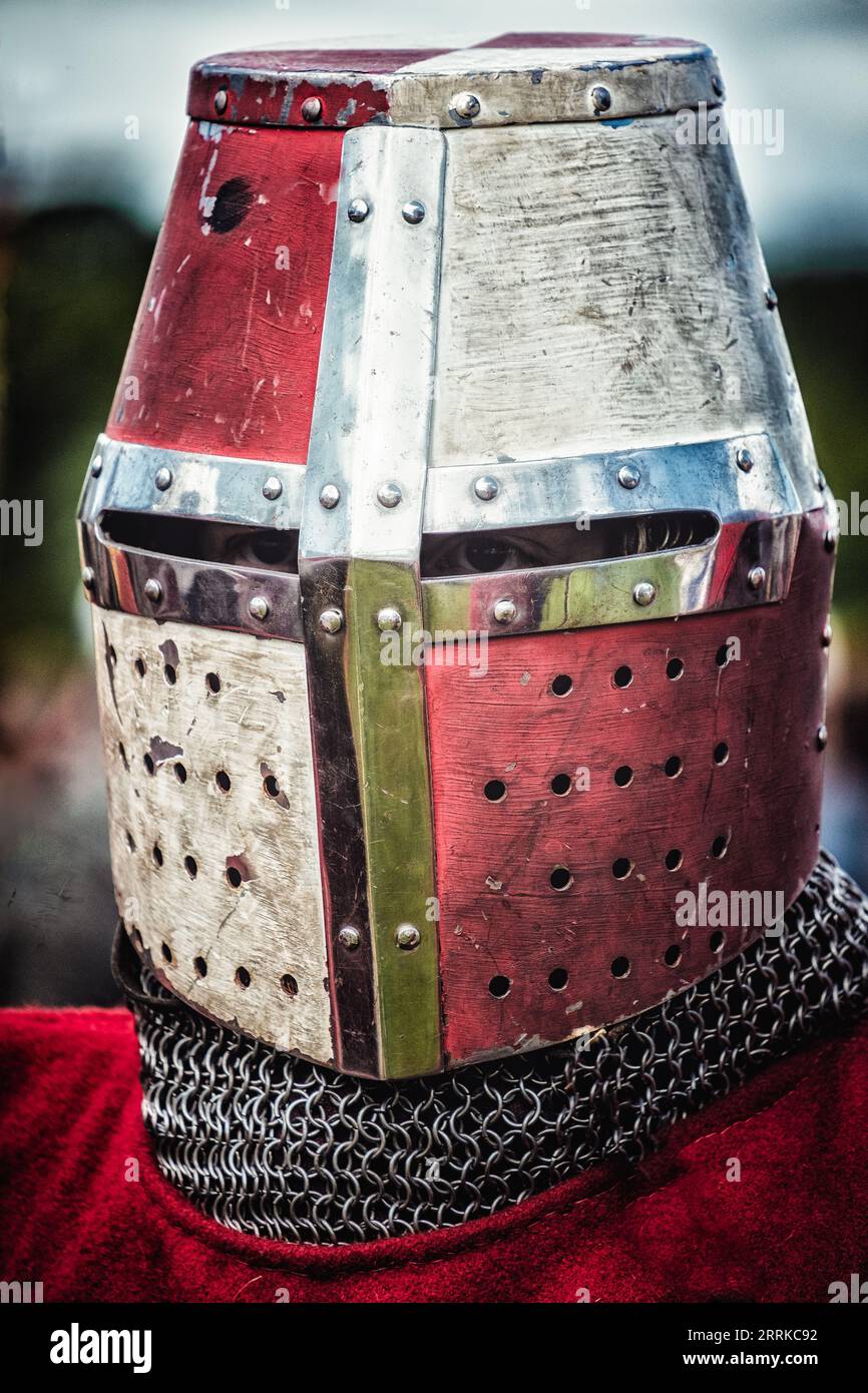 A portrait of a medieval knight wearing ornate protective armor, including a red, silver and green helmet with a chain encircling it Stock Photo