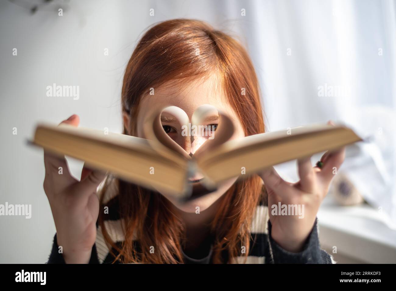A girl is holding a book. pages in the form of a heart. Reading, Knowing, Learning Stock Photo