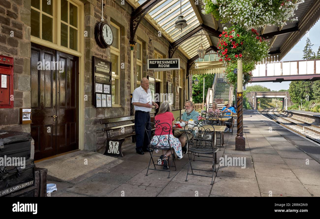 Winchcombe GWR preserved train station with passengers taking refreshments on the railway platform. Gloucestershire England UK Stock Photo