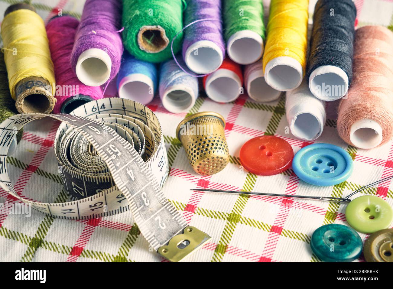 Sewing kit consisting needle, thimble, threads and measuring meter on a fabric background Stock Photo