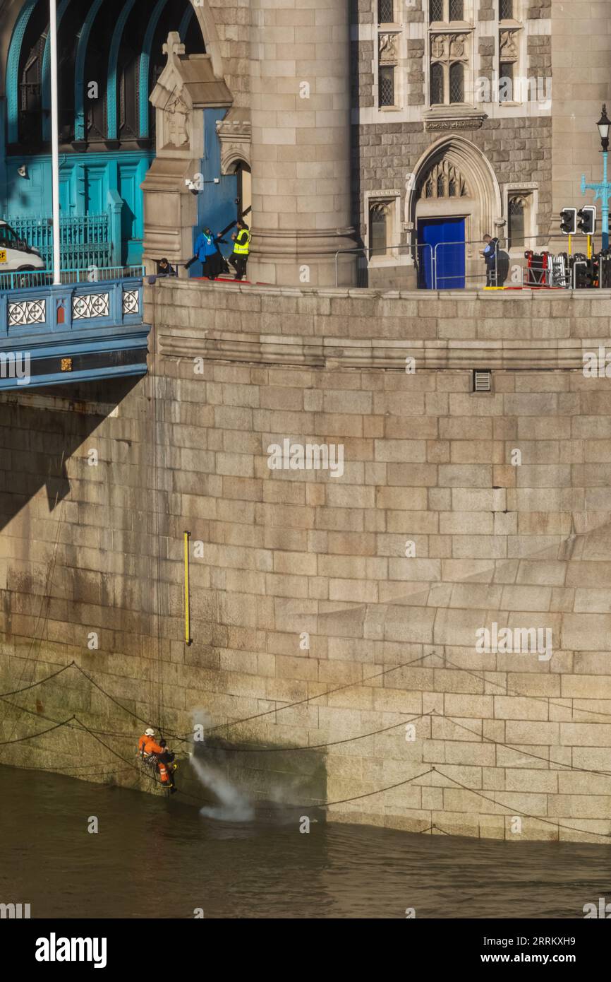 England, London, Tower Bridge, Maintenance Workers Using High Pressure Water Hose to Clean Base of Bridge at Low Tide Stock Photo