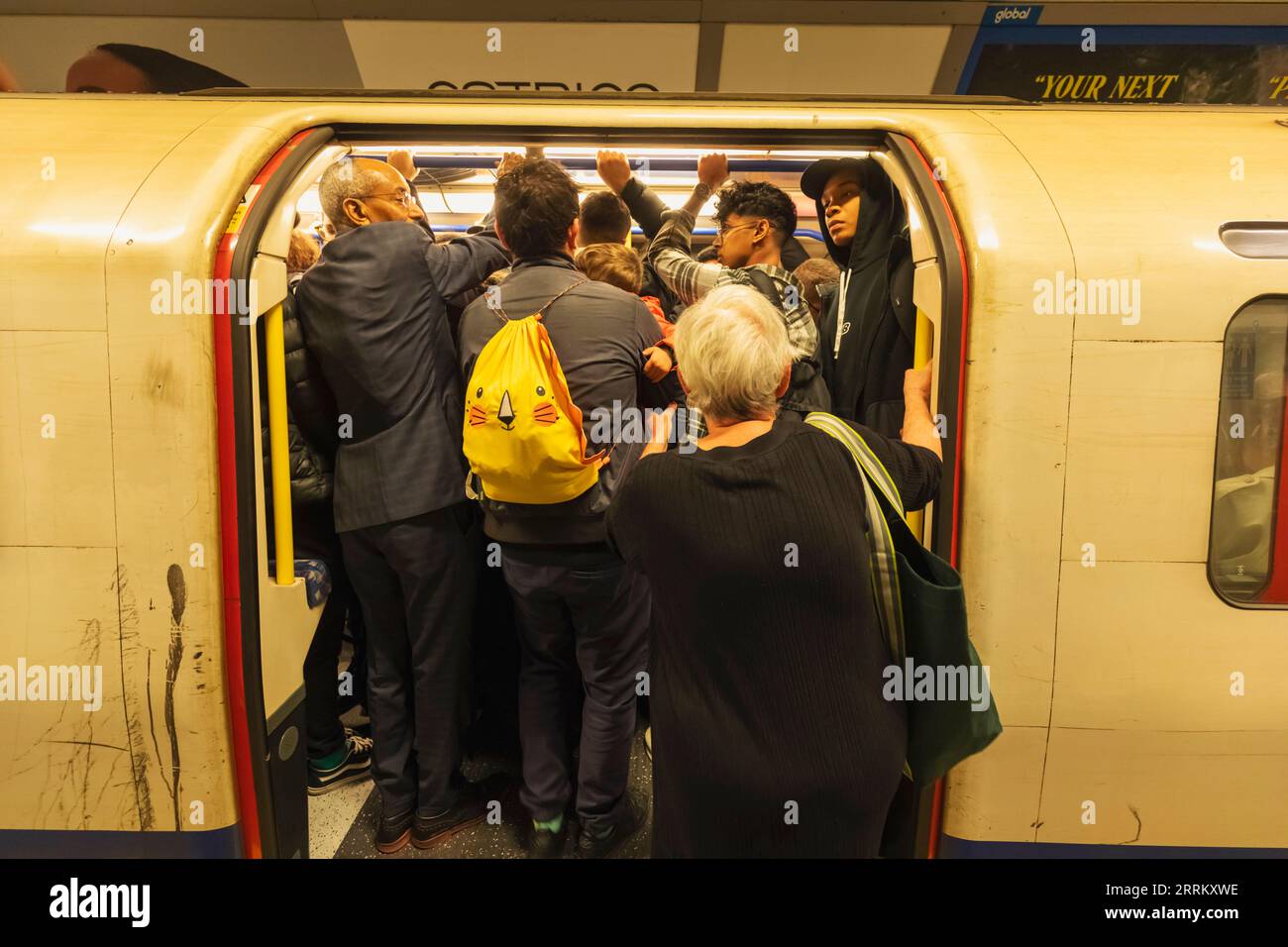 England, London, London Underground, Passengers Entering Overcrowded Train Carriage Stock Photo