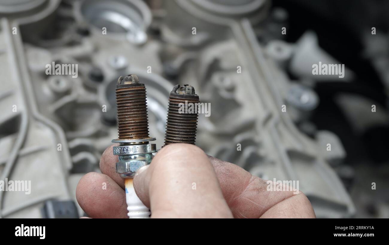 Vista, CA USA -September 3, 2023:  Close-up of old mechanic's hand holding corroded, damaged spark plugs Stock Photo