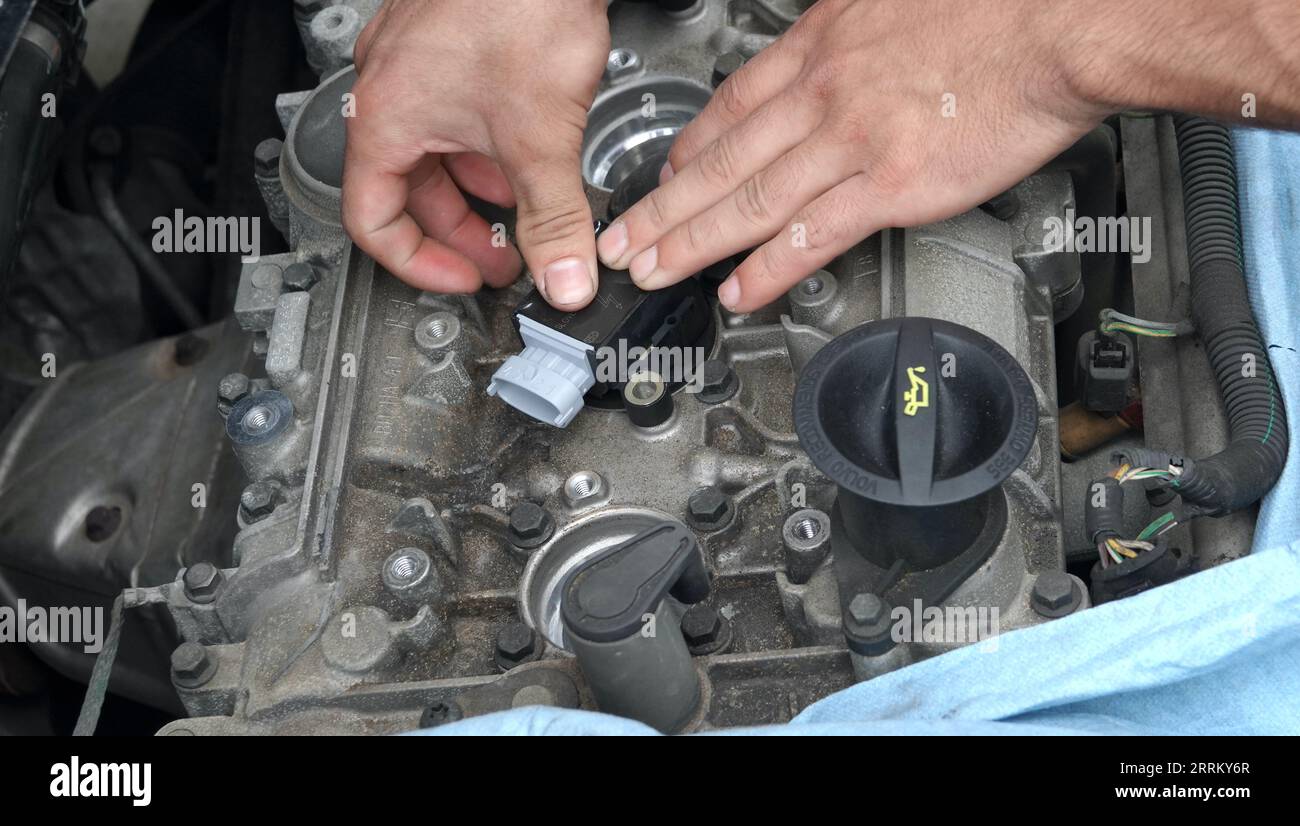 Vista, CA USA -September 3, 2023:  Young mechanic's hands pushing new ignition coil into place Stock Photo