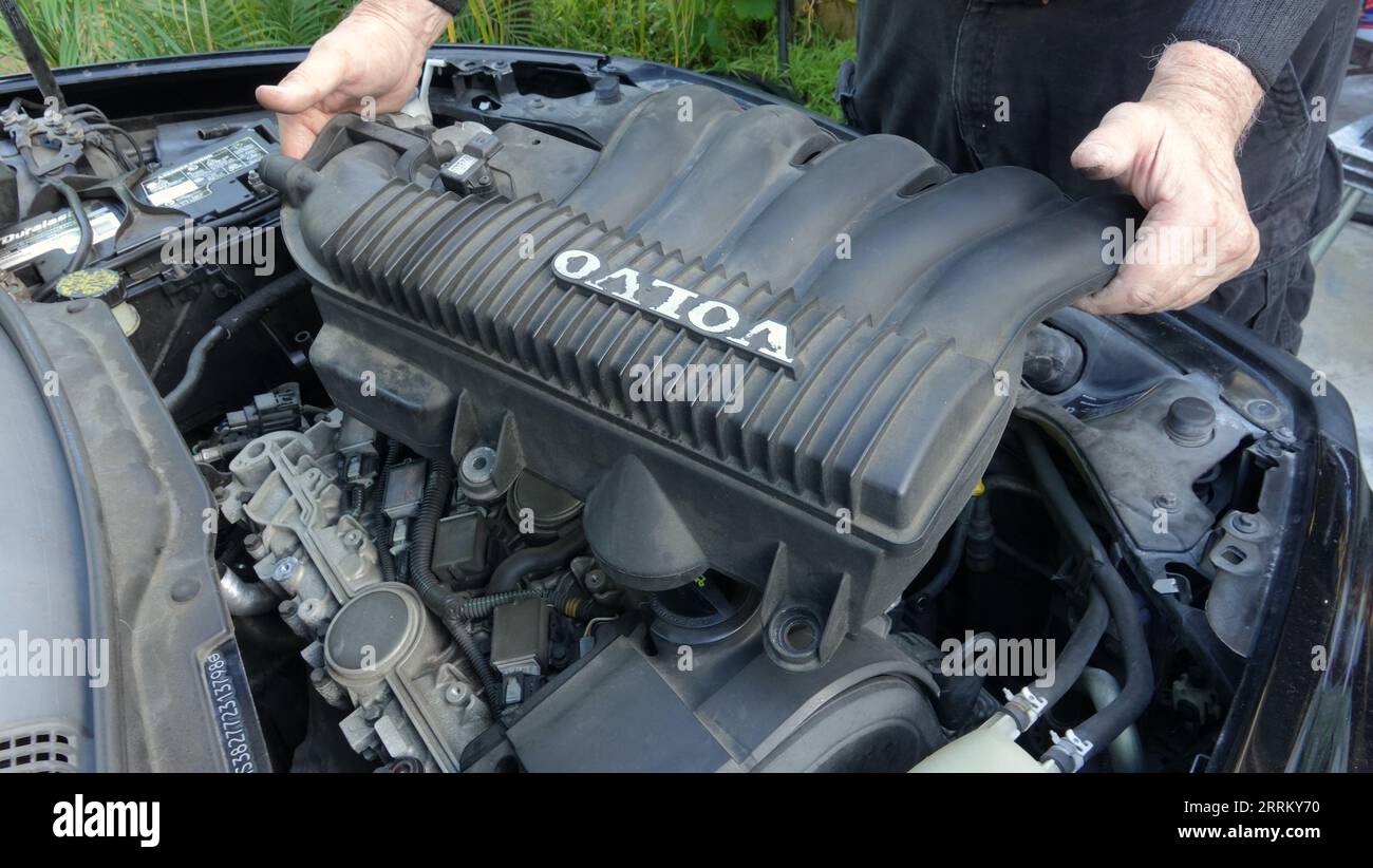 Vista, CA USA -September 3, 2023: Close up of old man's hands as he removes intake manifold on a 2007 Volvo S40 to get to the spark plugs Stock Photo