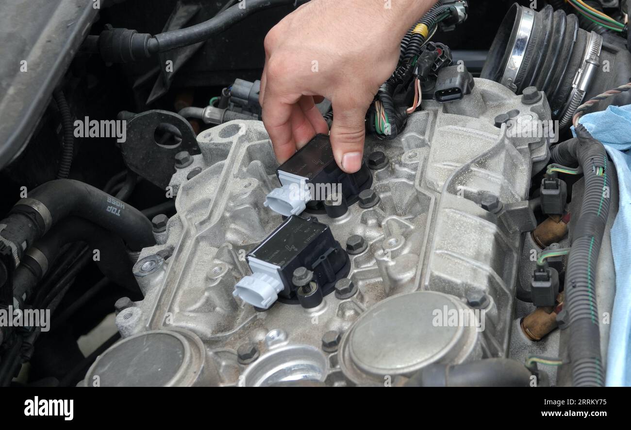 Vista, CA USA -September 3, 2023:  Young mechanic's hands pushing new ignition coil into place Stock Photo
